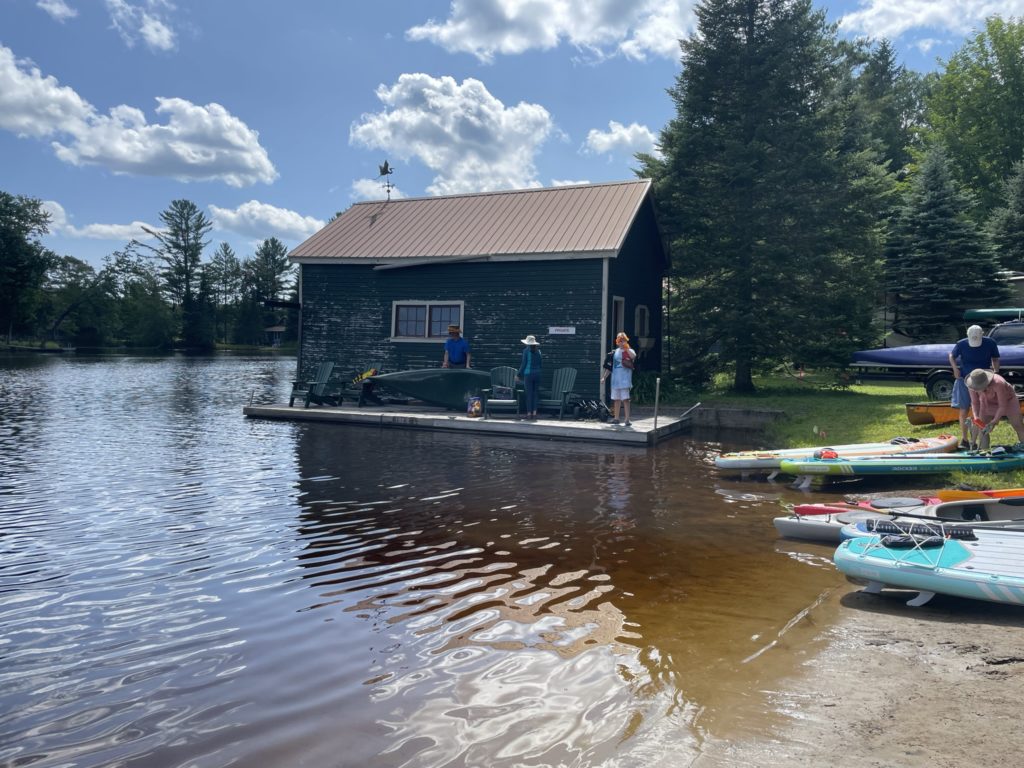 Photo of a boat house in Wanakena with kayakers about to begin the 2023 Poker Paddle